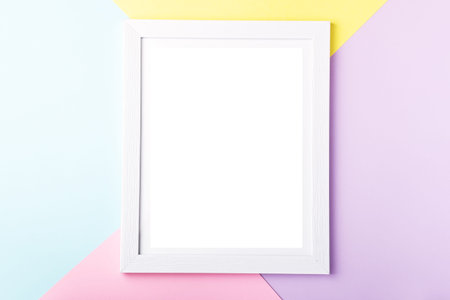 White picture frame on pastel pink, yellow, blue multicolor geometric background. Mockup on colorful...