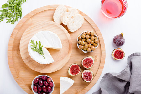 Traditional Spanish cuisine appetizers with brie cheese, figs, olives and wine on white table top