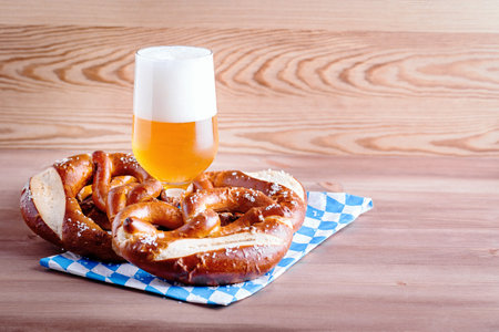 Oktoberfest background with beer and pretzels and traditional bavarian decor closeup on wooden table...