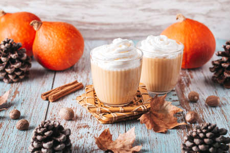 Autumn mood cozy flat lay with pumpkin latte, cedar pine cones, pumpkins and dried leaves on worn wood background, top view, Thanksgiving backgroundの写真素材