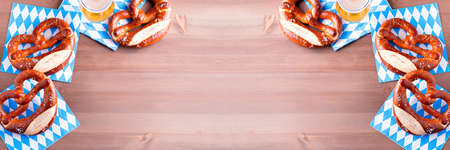 Oktoberfest background with beer and pretzels and traditional bavarian decor on wooden table topの写真素材