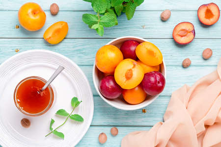 Yellow and red plums and jar of jam on worn wood table flat lay, autumn fruits conceptの写真素材