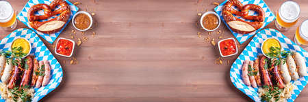 Oktoberfest table with traditional food - roasted sausages, pretzels, beer, sour cabbage on wooden table, top view, bannerの写真素材
