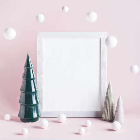 Christmas mockup frame with ceramic Christmas trees and white baubles on pink background. Minimalistic Christmas card with modern decor, copy spaceの写真素材