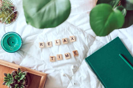 Cozy flat lay on white blanket with plants, headphones, candle, succulent and words relax time top viewの写真素材