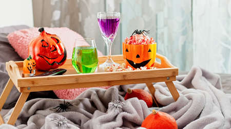 Tray on bed with halloween decor, popcorn, drinks and remote controller. Halloween background for movie night, pastime idea for holidayの写真素材