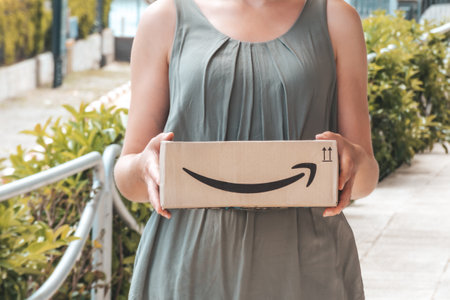 EMPURIABRAVA, SPAIN- JUNE 12, 2020: woman receiving Amazon delivery. Amazon box in woman hands closeupのeditorial素材