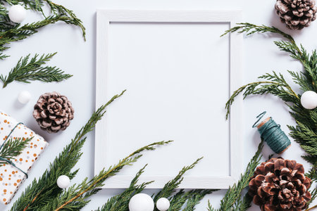 Stylish white and green Christmas flat lay with huge pine cones, cedar branches, presents and...