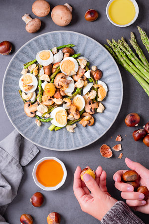 Salad with chestnuts, mushroom, asparagus and eggs on grey stone background, top view, autumn dish,...