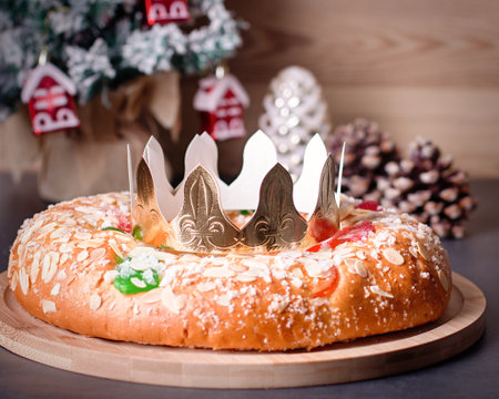Traditional Epiphany cake Roscon de Reyes on wooden table top with small Christmas tree, wrapped gifts and decoration closeup, top viewの写真素材