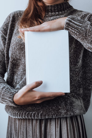 Woman holding stack of books, books closeup, blurry background