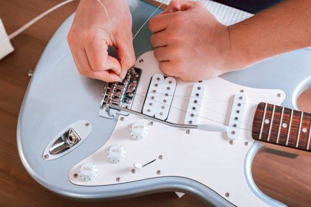 Guitar master restringing electric guitar, top view, closeup