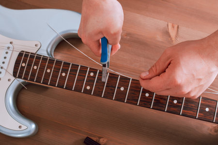 Guitar master restringing electric guitar, top view, closeup
