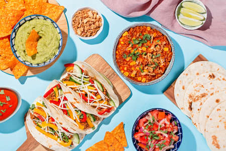 Mexican food table with traditional dishes. Chili con carne, tacos, tomato salsa, corn chips with guacamoleの写真素材
