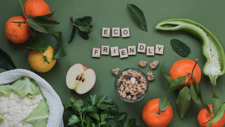 Flat lay with fresh local vegetables and fruits on green background and eco friendly quoteの写真素材