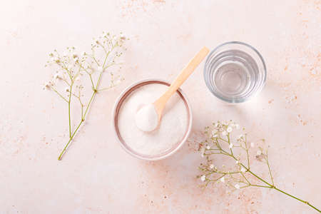 Collagen powder and glass of water on beige stone background, top viewの写真素材