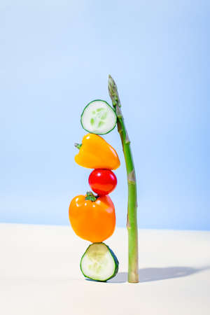 Creative food balance, vegetables equilibrium shot on blue background.の写真素材