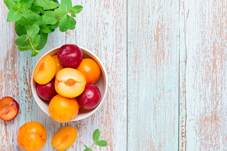 Yellow and red plums in a plate on blue wooden table flat lay, autumn fruit preserves concept, copy spaceの写真素材
