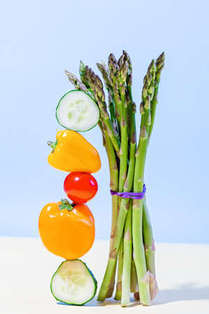 Balance image with fresh raw vegetables asparagus, cucumber, mini sweet peppers and tomato. Equilibrium creative food composition.の写真素材