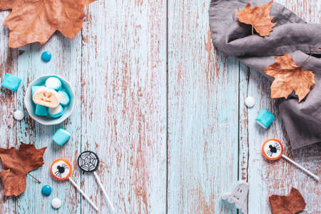 Halloween sweet treats frame on blue wooden table. Halloween background, flat lay, copy spaceの写真素材