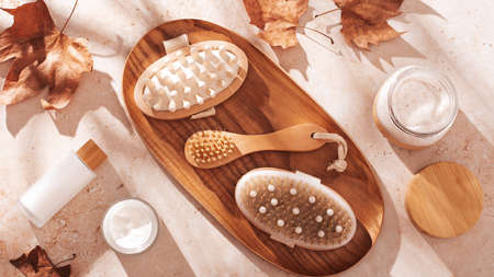 Autumn face and body cosmetics and accessories for autumn beauty care. Seasonal beauty products in eco friendly wooden bottles and wooden beauty accessories flat lay with shadows in hard lightの写真素材
