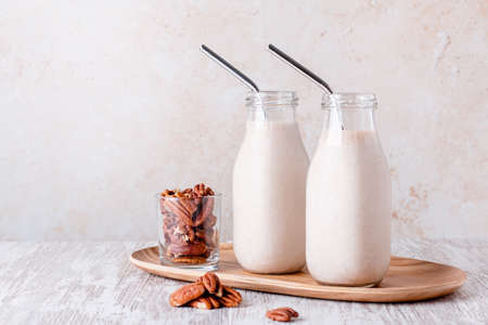 Pecan milk in glass bottles on wooden trayの写真素材