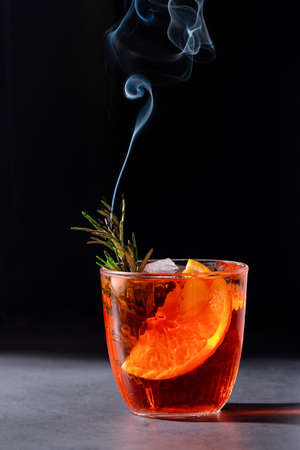 Negroni cocktail with smoking rosemary and orange garnish on black background, minimal styleの写真素材
