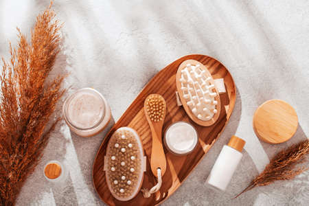 Body brushes and face and body care cosmetics on concrete table with pampas grass, top view, copy space.の写真素材
