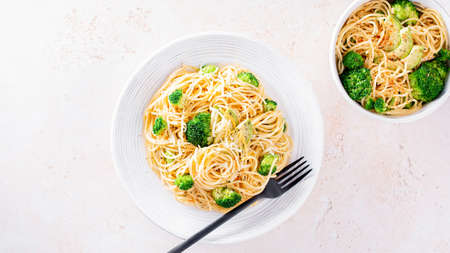 Broccoli and avocado pasta with grated cheese, healthy green meatless dish on table with ingredients, top viewの写真素材