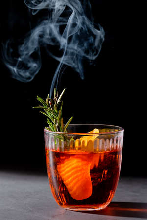 Negroni cocktail with smoking rosemary and orange garnish on black backgroundの写真素材