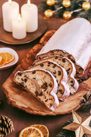 Christmas Stollen background with golden decor, Christmas tree branches and candles on wooden table, top viewの写真素材