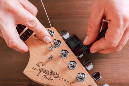 EMPURIABRAVA, SPAIN - FEBRUARY 17, 2021 Guitar master changing guitar strings on Fender Squier Strat