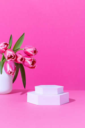 Pink podium for product display on pink with tulips flowers in hard lightの写真素材