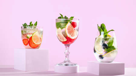 Summer refreshing fruit and berry infused water, detox drinks on podiums, creative summer beverages on stands on pink background, minimal styleの写真素材