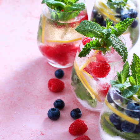 Raspberry, lemon and blackberry infused water in glasses on pink table, copy spaceの写真素材