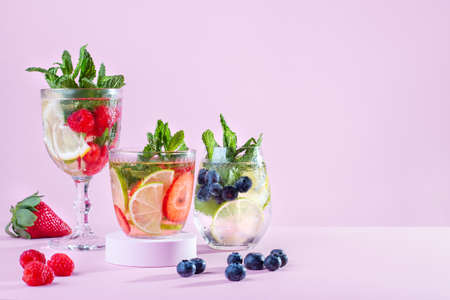 Summer refreshing fruit and berry infused water, detox drinks on podiums, creative summer beverages on stands on pink background, minimal styleの写真素材