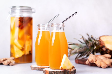 Fermented pineapple beverage tepache in reusable glass bottles with metal drinking straws and glass...