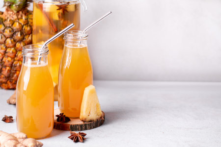 Fermented pineapple beverage tepache in reusable glass bottles with metal drinking straws and glass...