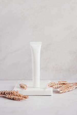 White blank cosmetic under eyes cream bottles and wheat for mock up on white marble tray. beauty product packagingの写真素材