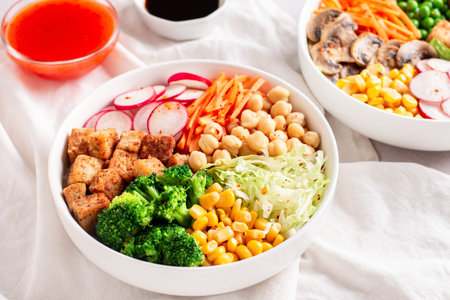 Vegan buddha bowl with tofu, colorful vegetables on base of brown rice with sauces. Top view,...