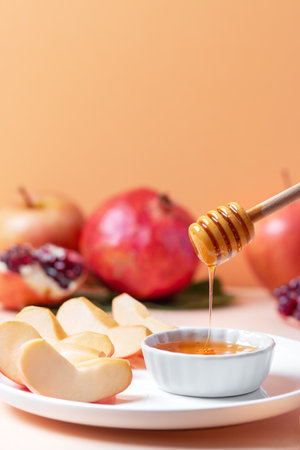 Apples and honey closeup for Jewish holiday Rosh Hashanah with pomegranate in backgroundの写真素材