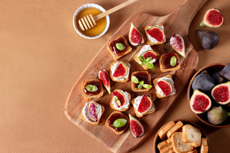 Toasts with figs, ricotta and fig marmalade sprinkled with honey on wooden board, top view. Autumn season snack with fresh produceの写真素材