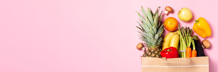 Fresh fruits and vegetables in paper bag on pastel pink background, web banner, top view, copy...