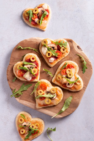 Heart shape mini pizzas on wooden board for Valentines day holiday, top view. Valentines day food in shape of heartの写真素材