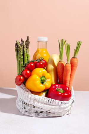 Raw colorful fresh vegetables in white mesh bag on table in hard light. Healthy eating, eco friendly grocery shopping concept.の写真素材