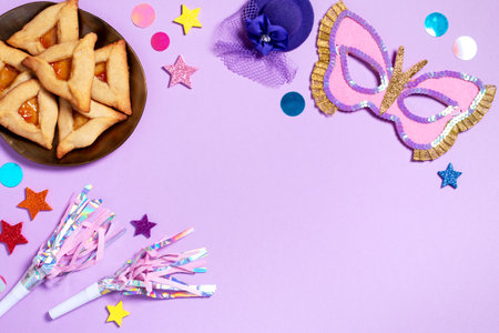 Purim carnival border with traditional cookies, costume accessories and decor on pastel violet background, copy space, toned imageの写真素材
