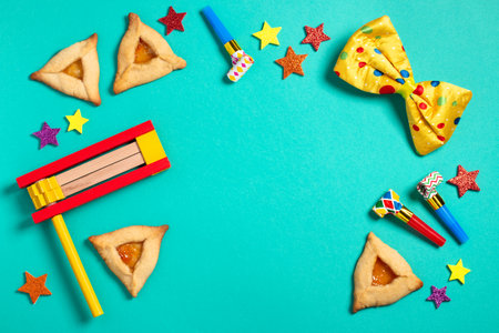 Purim border, carnival background with traditional hamantaschen cookies, costume accessories and decor on bright green background, copy spaceの写真素材
