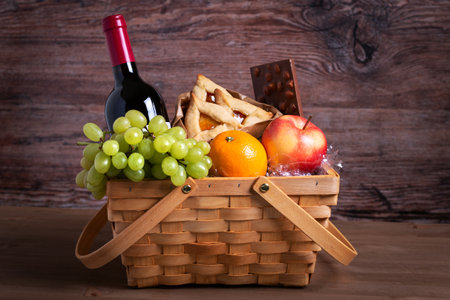 Purim basket, Purim gift with foods, cookies, fruits and wine on wooden table.の写真素材