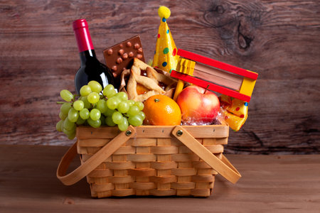 Purim basket, Purim gift basket with foods, wine, gragger and carnival costume accessories on wooden table.の写真素材