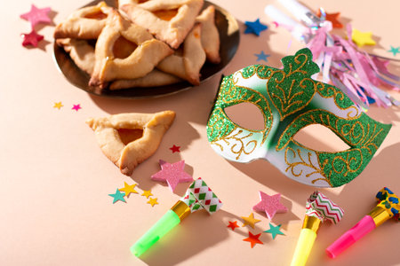 Purim carnival background with traditional hamantaschen cookies, carnival mask, holiday decor in hard light, copy spaceの写真素材